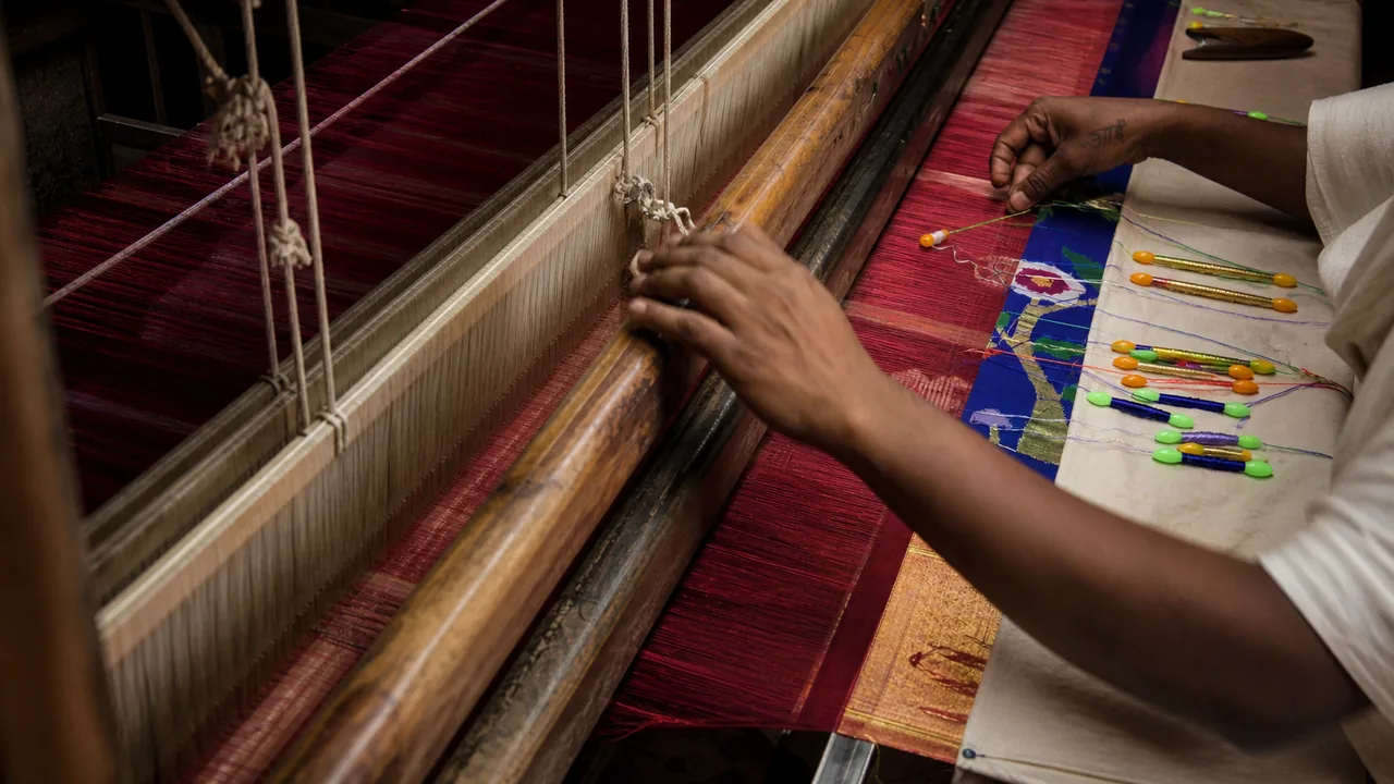 Artisan hands weaving Paithani silk on a traditional wooden handloom